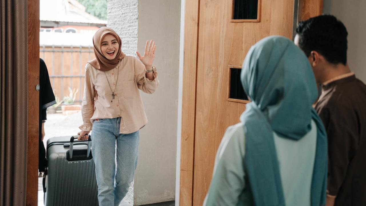 A couple is welcoming a visitor at their doorstep