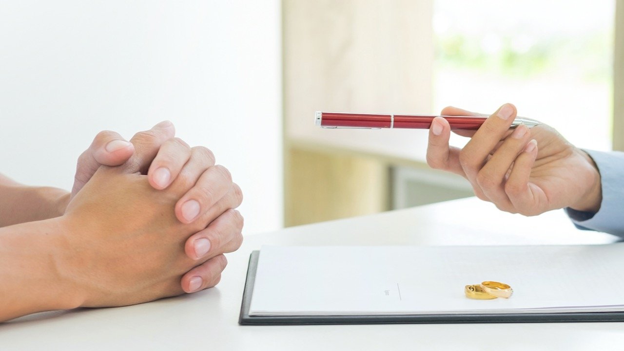 Two people discussing divorce with two rings on the table