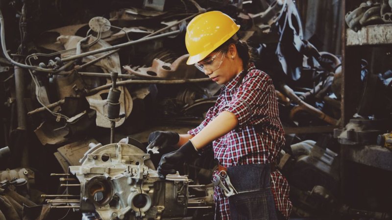 Women with yellow helmet working at a machine