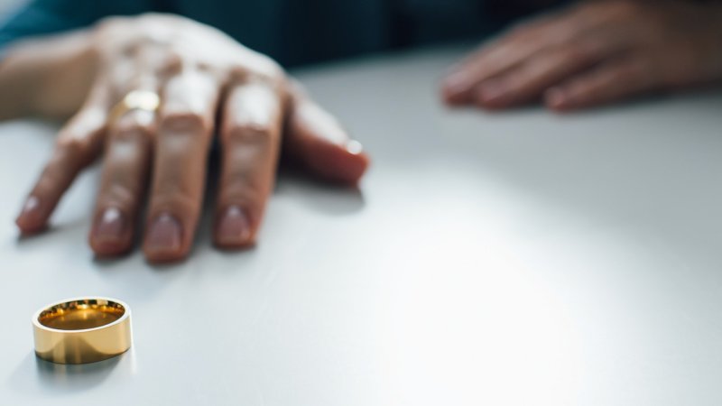 Person sitting next to table with a wedding ring on it