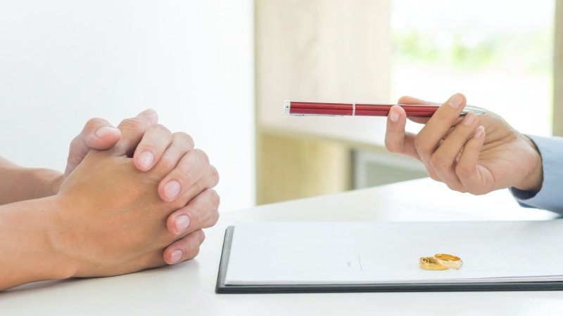 Two people discussing divorce with two rings on the table